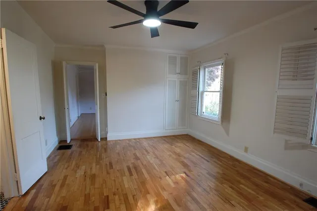 a view of empty room with wooden floor and fan