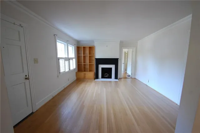 an empty room with wooden floor a fireplace and windows