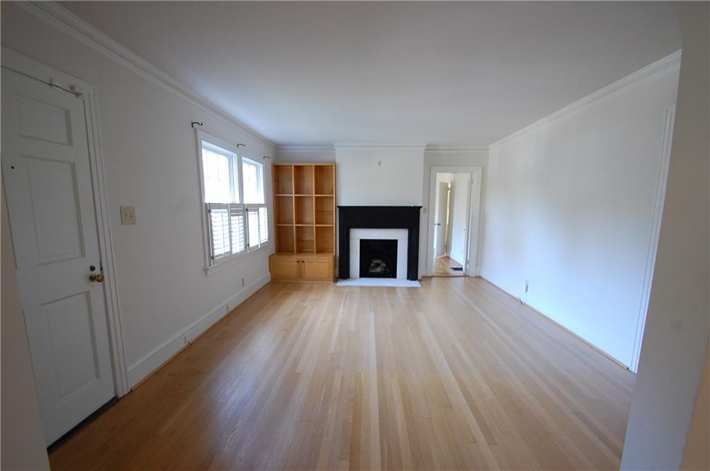 3347 College Street Atlanta, GA 30337 - Photo 4 of 39 an empty room with wooden floor a fireplace and windows