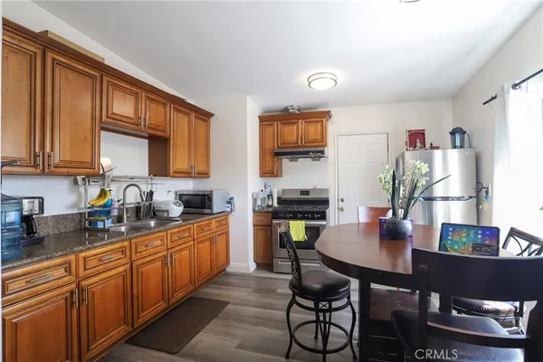 a kitchen with stainless steel appliances granite countertop a refrigerator a sink dishwasher a dining table and chairs with wooden floor