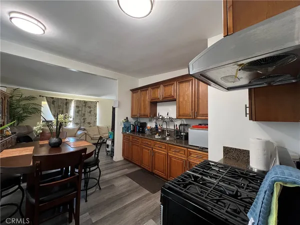 a kitchen with stainless steel appliances granite countertop a refrigerator a sink dishwasher a dining table and chairs with wooden floor