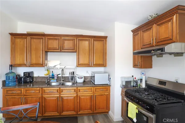 a kitchen with stainless steel appliances granite countertop a stove a sink dishwasher and cabinets with wooden floor
