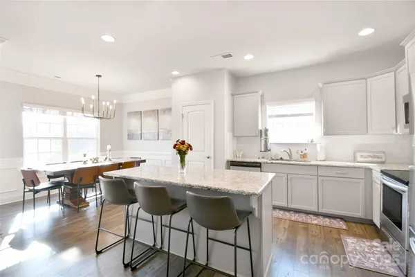 a kitchen with granite countertop a stove a sink a dining table and chairs
