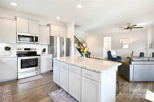 a kitchen with stainless steel appliances kitchen island granite countertop a sink stove and refrigerator
