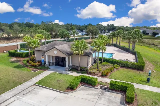 a view of a house with a big yard plants and large trees