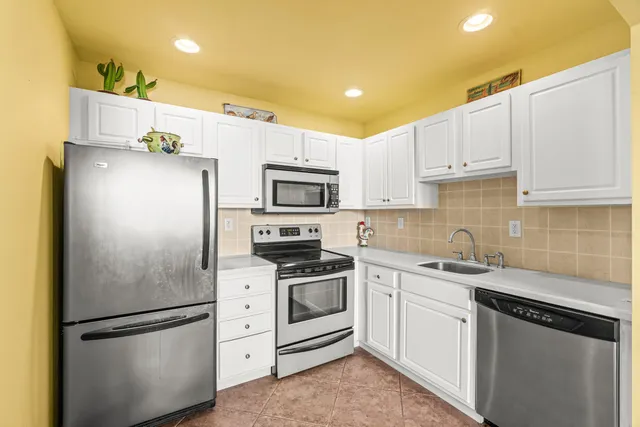 a kitchen with white cabinets and stainless steel appliances