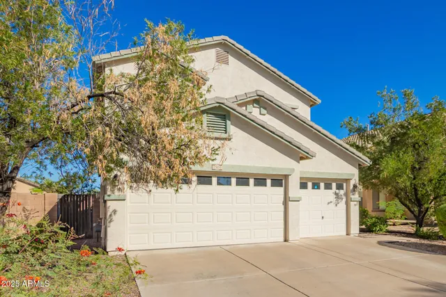 a view of a white house with a large tree and windows