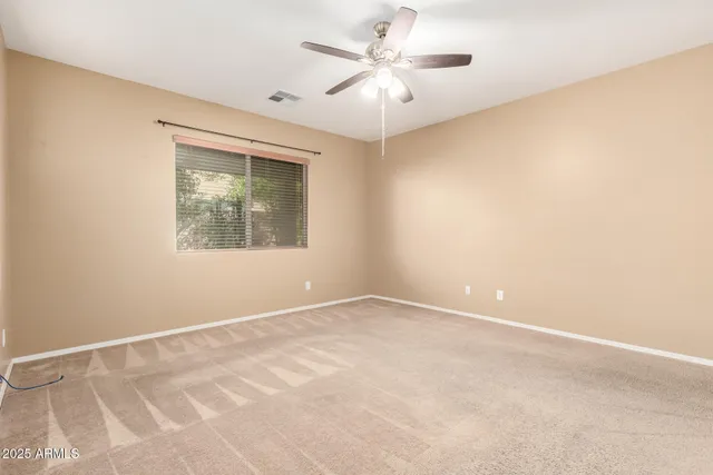 an empty room with a window and a ceiling fan