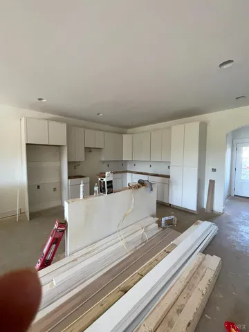 a living room with stainless steel appliances furniture a rug and a kitchen view