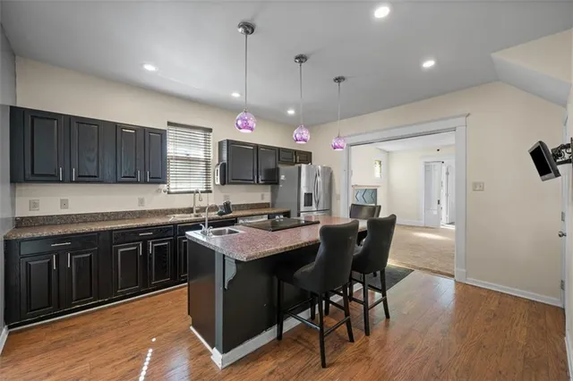 a kitchen with stainless steel appliances granite countertop a stove top oven a refrigerator a sink and chairs