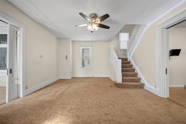 wooden floor in an empty room with a ceiling fan and window