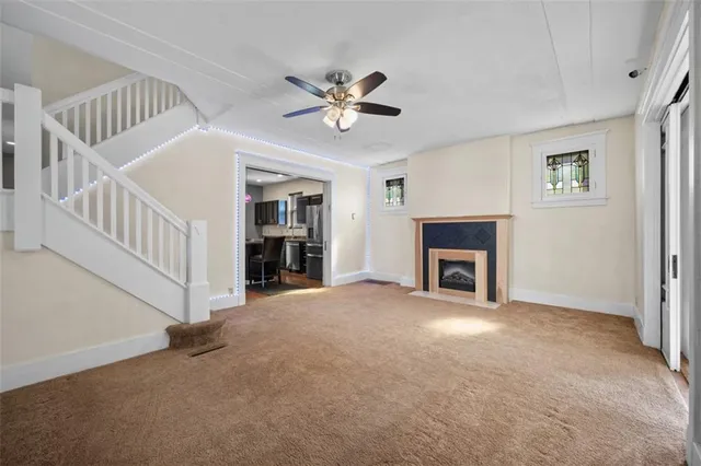 a view of a livingroom with a ceiling fan a fireplace and a window