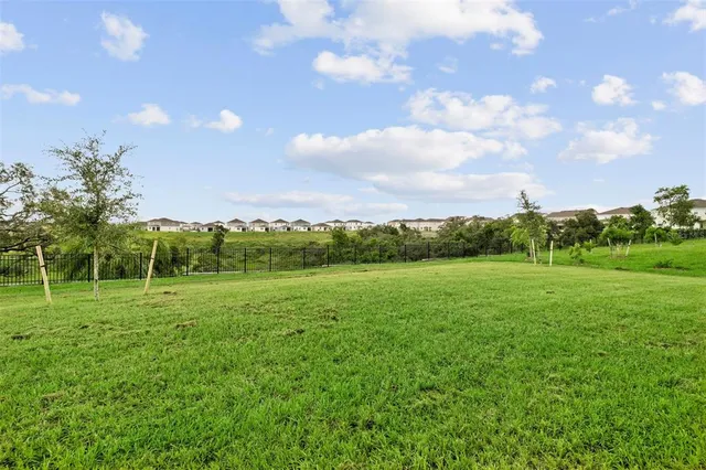 a view of a white house with a big yard and large trees