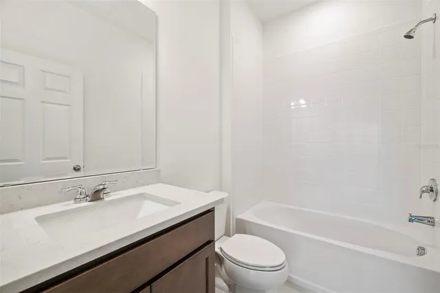 a bathroom with a granite countertop sink a toilet and bathtub