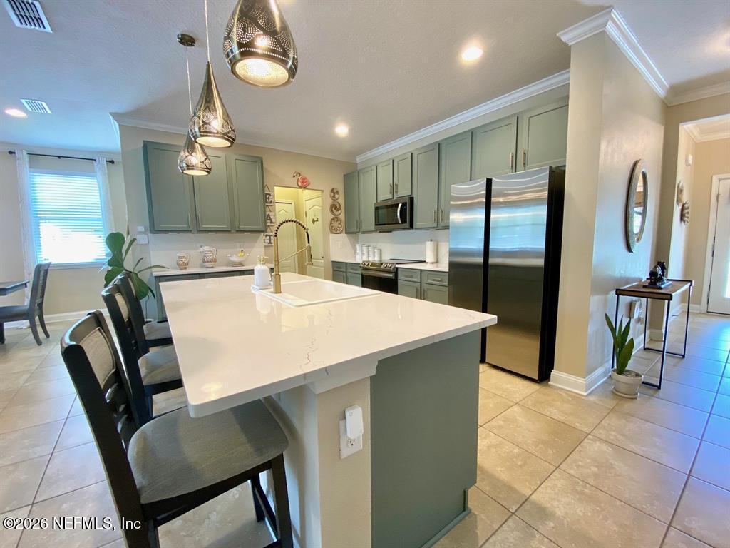 115 Sierras Loop St. Augustine, FL 32086 - Photo 15 of 65 a kitchen with stainless steel appliances a table chairs and a refrigerator