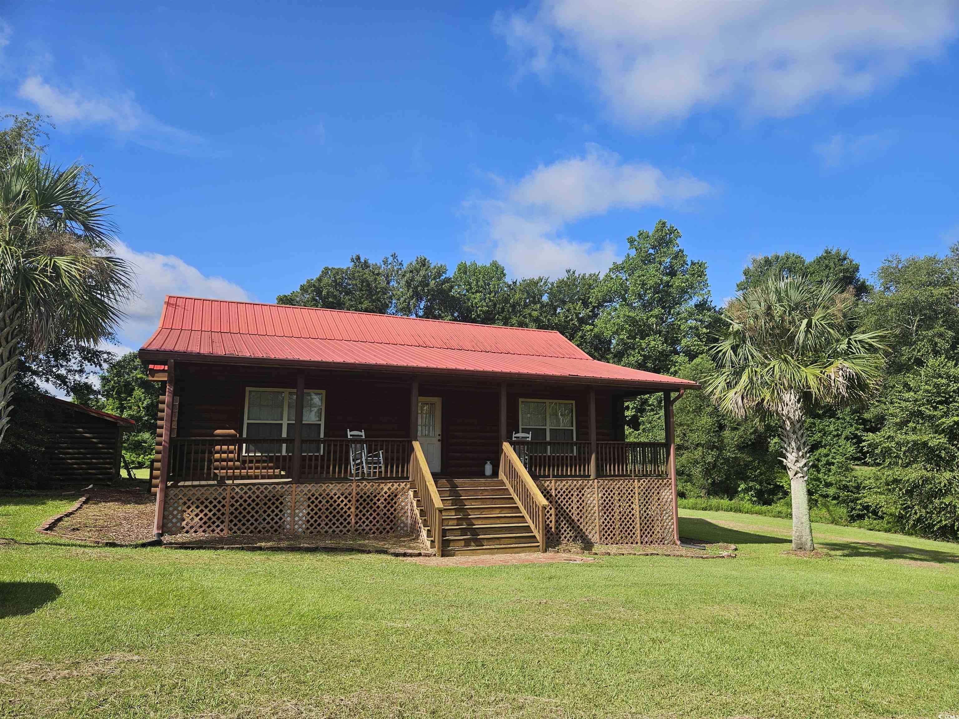 View of front of house with covered porch, a front lawn, a metal roof, and stairway