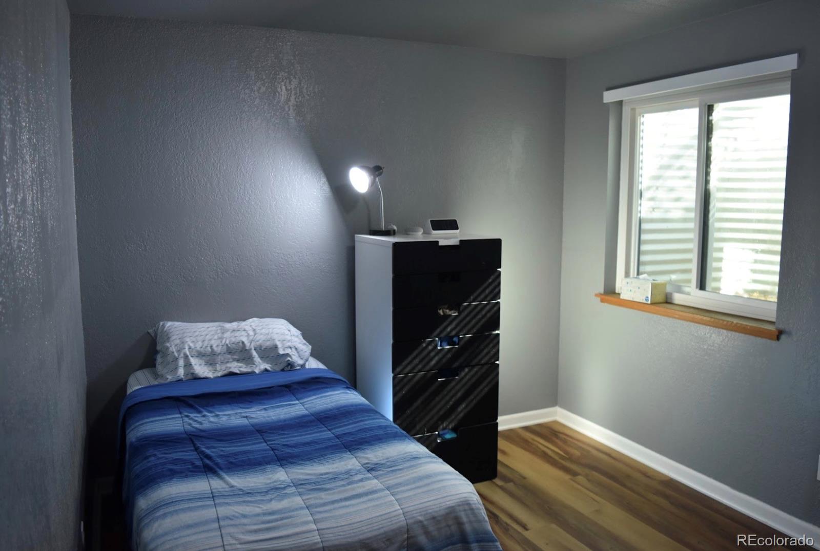 1426 3rd Street Fort Lupton, CO 80621 - Photo 30 of 50 a bedroom with a bed and wooden floor