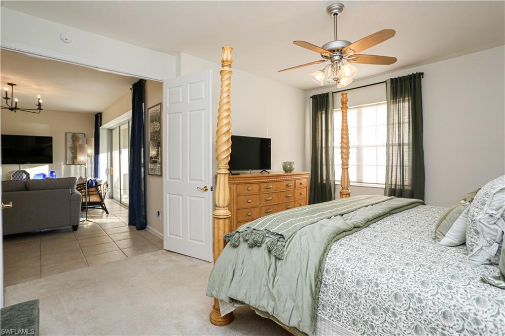 3930 Deer Crossing Court, Unit 3103 Naples, FL 34114 - Photo 45 of 50 a bedroom with a large bed a flat tv screen and a chandelier
