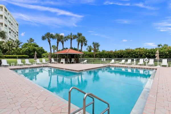 a view of a swimming pool with a table and chairs under an umbrella