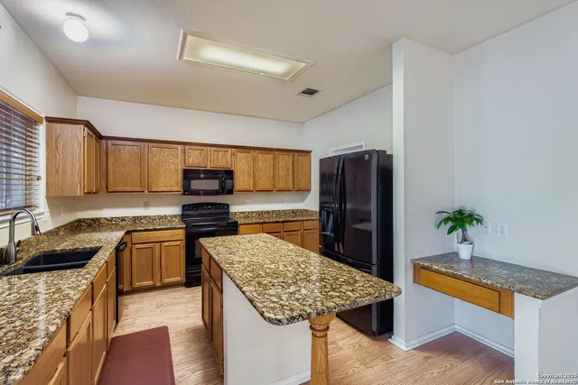 a kitchen with stainless steel appliances granite countertop a sink dishwasher stove and refrigerator with wooden floor
