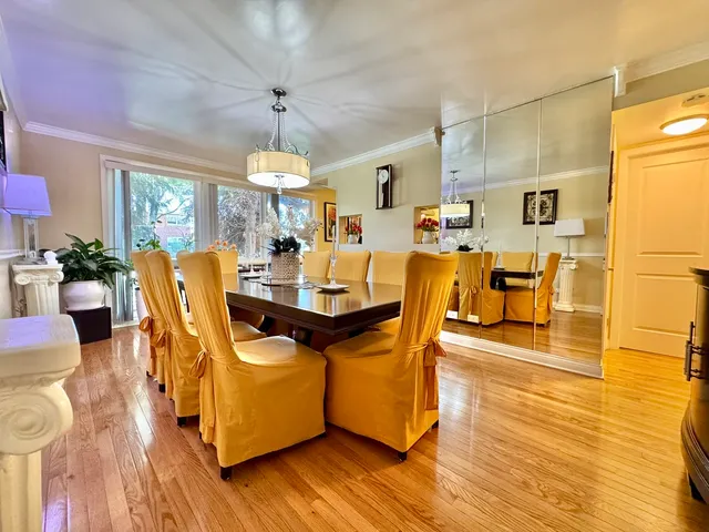 a dining room with wooden floor a chandelier a wooden table and chairs