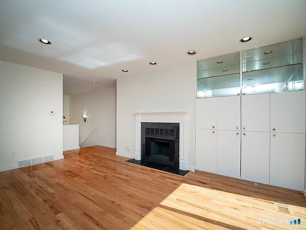 a view of an empty room with wooden floor and a fireplace
