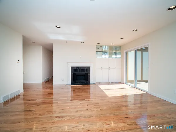 a view of empty room with wooden floor and kitchen view