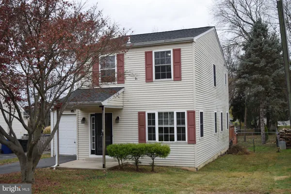 a front view of a house with a garden and trees
