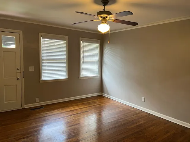 a view of a room with wooden floor fan and windows
