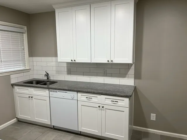 a kitchen with granite countertop white cabinets and white appliances