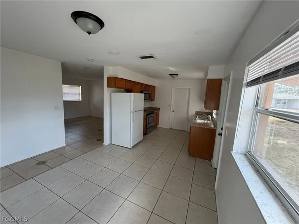 a view of a refrigerator in kitchen and a window