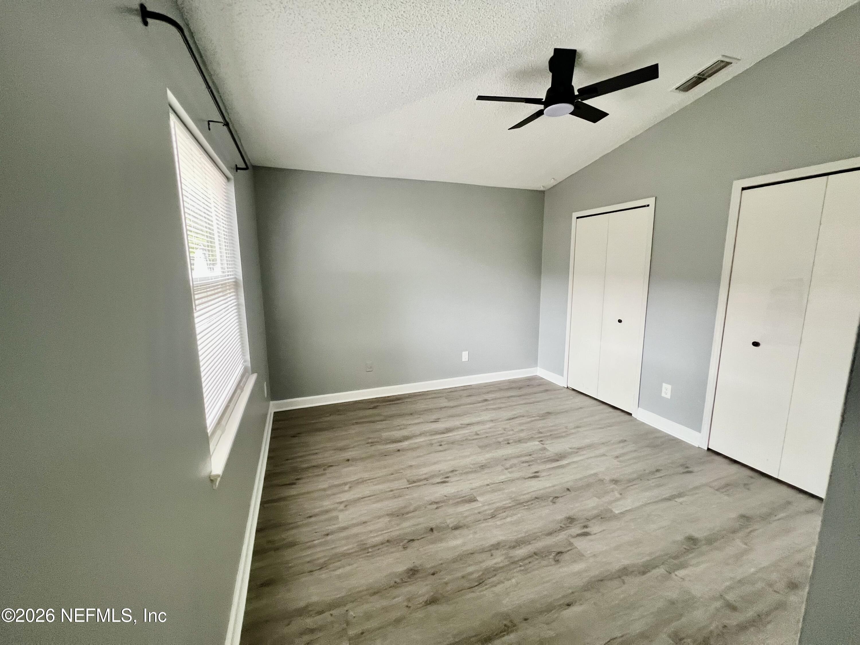 8778 Buzz Court Jacksonville, FL 32216 - Photo 12 of 22 a view of empty room with wooden floor and fan