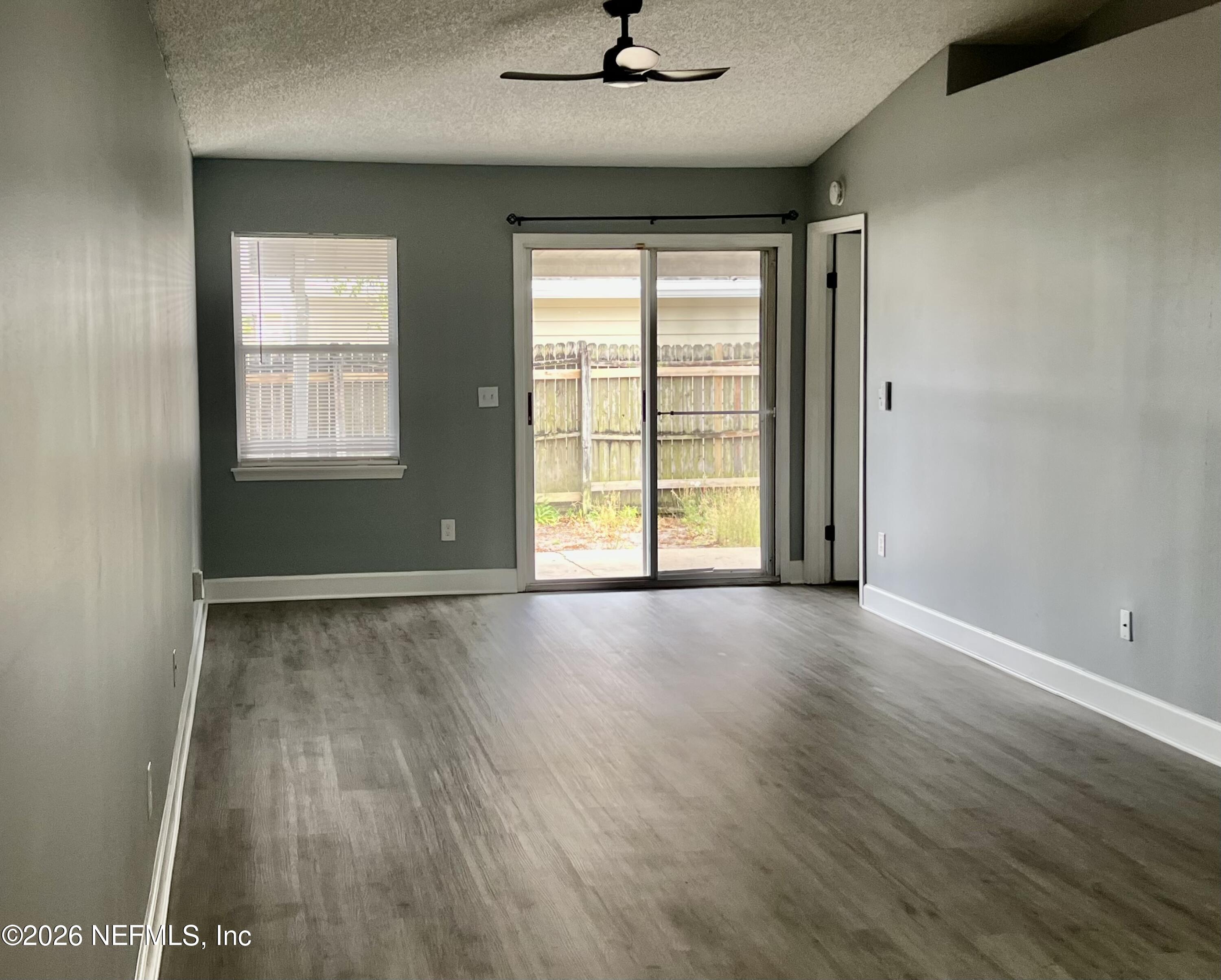 8778 Buzz Court Jacksonville, FL 32216 - Photo 5 of 22 an empty room with wooden floor and windows