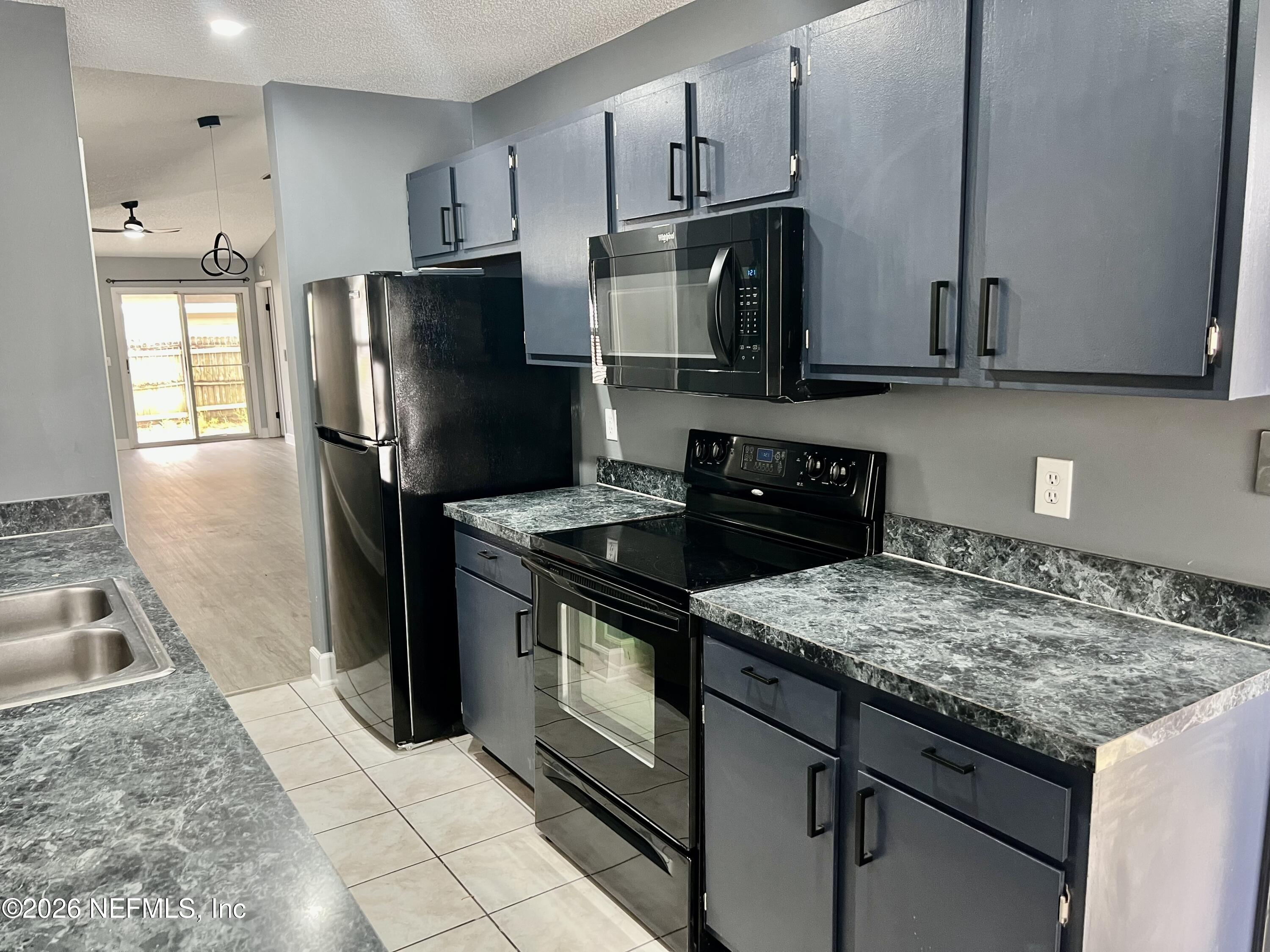 8778 Buzz Court Jacksonville, FL 32216 - Photo 8 of 22 a kitchen with granite countertop a refrigerator stove and sink