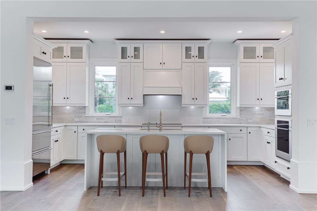 1375 Sandy Lane Vero Beach, FL 32963 - Photo 5 of 36 a kitchen with granite countertop white cabinets and chairs