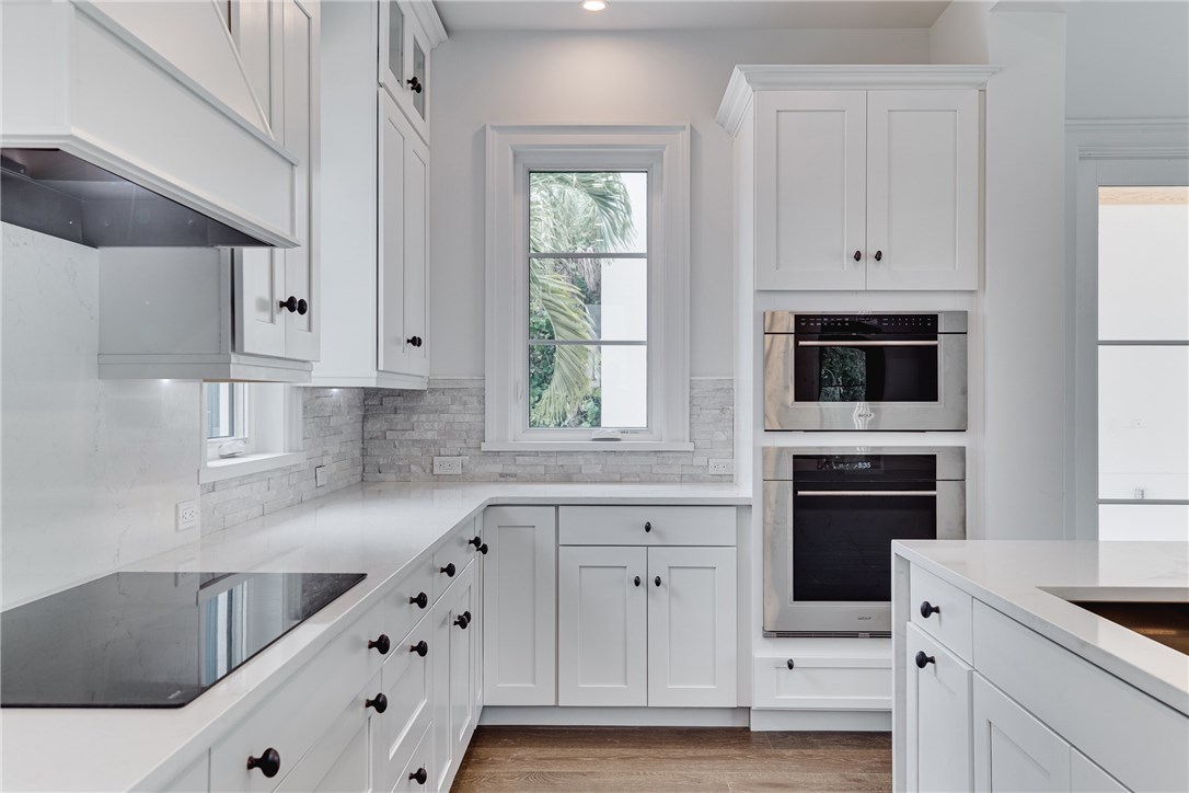 1375 Sandy Lane Vero Beach, FL 32963 - Photo 7 of 36 a kitchen with granite countertop white cabinets and black appliances