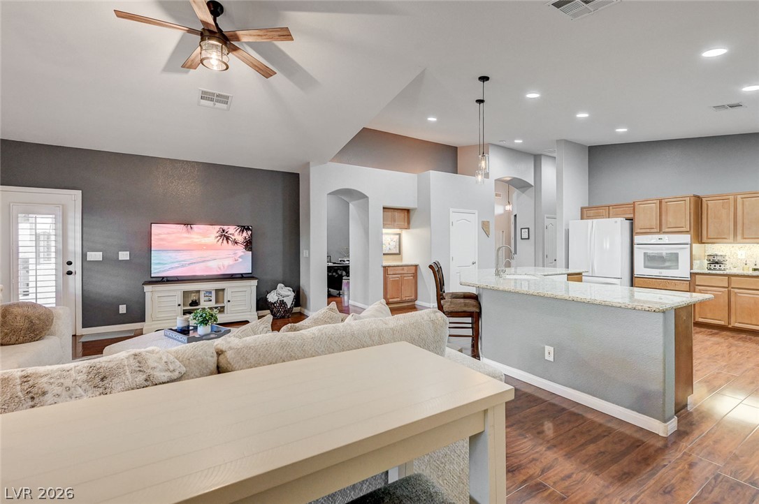1604 Cattle Ranch Place Henderson, NV 89002 - Photo 29 of 99 An inviting open-concept living space features wood flooring, a ceiling fan, and a kitchen island with granite counters.