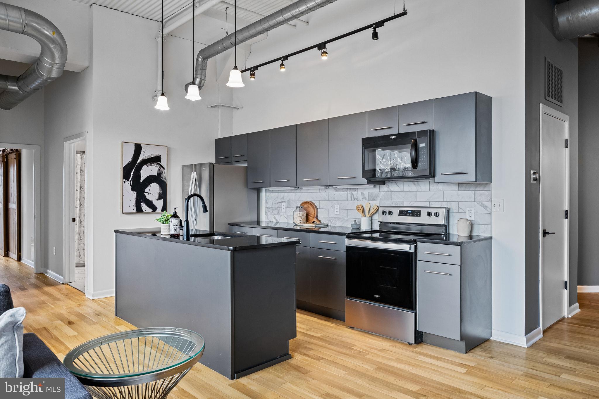 2200-28 Arch Street, Unit 612 Philadelphia, PA 19103 - Photo 22 of 43 a kitchen with stainless steel appliances granite countertop a sink dishwasher stove and refrigerator with wooden floor