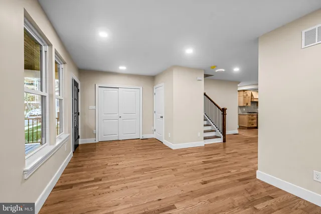 a view of a hallway with wooden floor and a bathroom