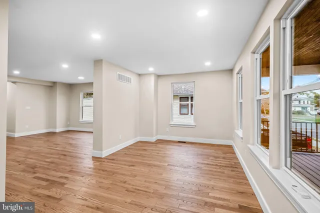a view of an empty room with window and wooden floor