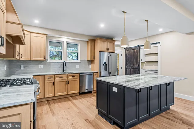 a kitchen with stainless steel appliances granite countertop a refrigerator a sink dishwasher a stove and a refrigerator with wooden floor