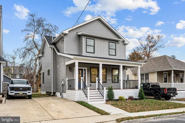 a view of a white house with a small yard and large trees