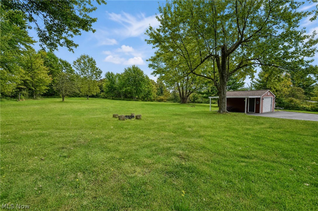 3864 State Road South Ashtabula, OH 44004 - Photo 41 of 50 Expansive green lawn with mature trees and a detached garage featuring a white overhead door