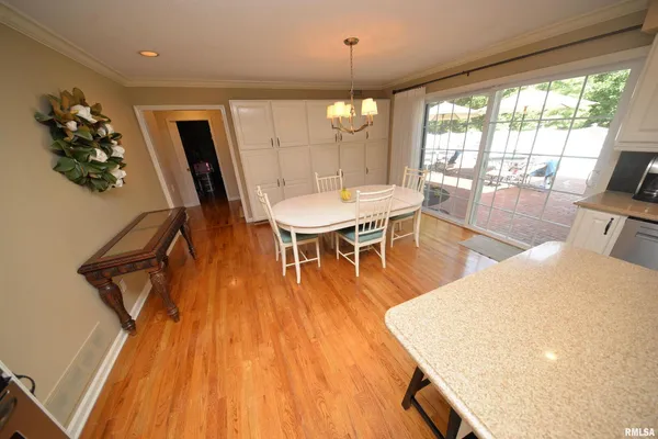 a kitchen with granite countertop a refrigerator a stove a sink and white cabinets with wooden floor