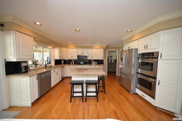a large kitchen with kitchen island a large counter space a sink a window and stainless steel appliances