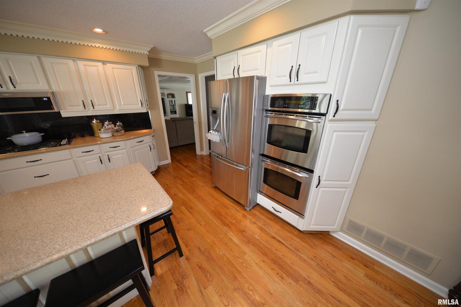 616 Seville Drive Mount Vernon, IL 62864 - Photo 29 of 62 a kitchen with granite countertop a refrigerator a stove a sink and white cabinets with wooden floor