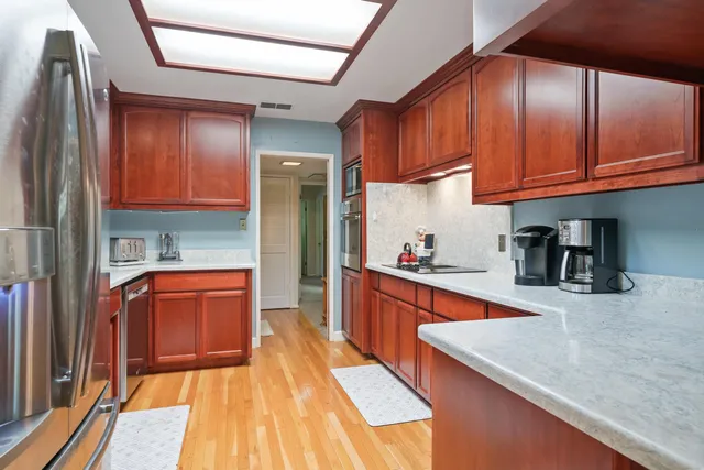 a kitchen with stainless steel appliances granite countertop wooden cabinets a oven and granite counter tops with a large window