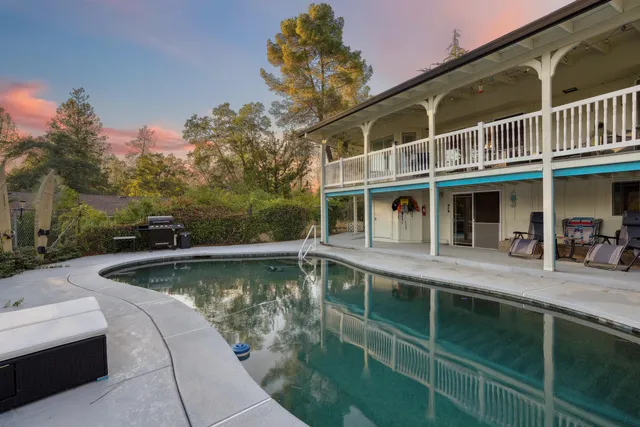 a view of a swimming pool with a bench in front of house