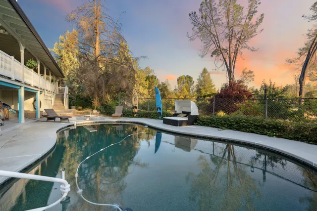 a view of swimming pool with seating area and trees around