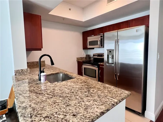 a kitchen with stainless steel appliances granite countertop a sink a refrigerator and a stove